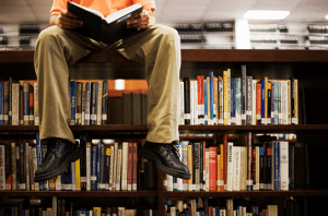 mans sitting on top bookcase photo